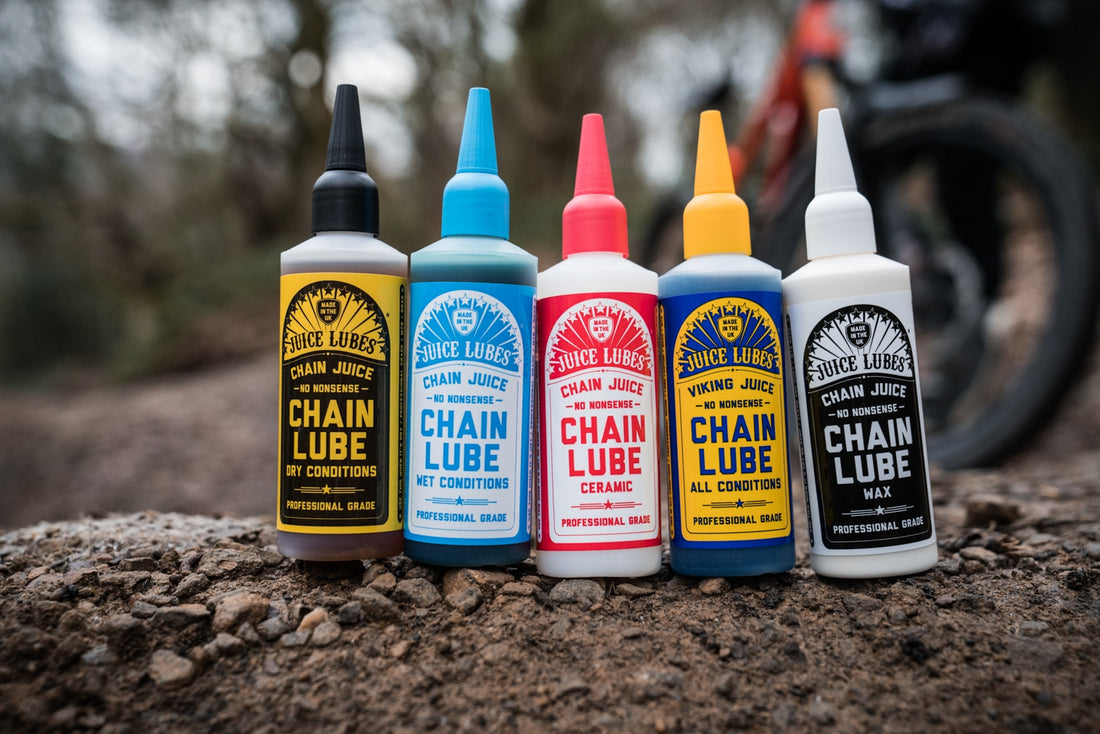 Five Juice Lubes Chain Juice bottles on rocky ground: dry, wet, ceramic, all-conditions Viking, and wax chain lube