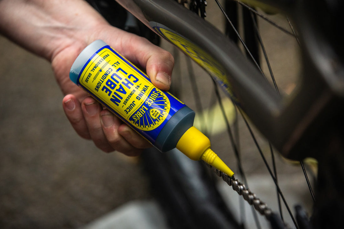 Mechanic applying Juice Lubes Chain Juice lube to a bicycle chain through the squeeze bottle nozzle