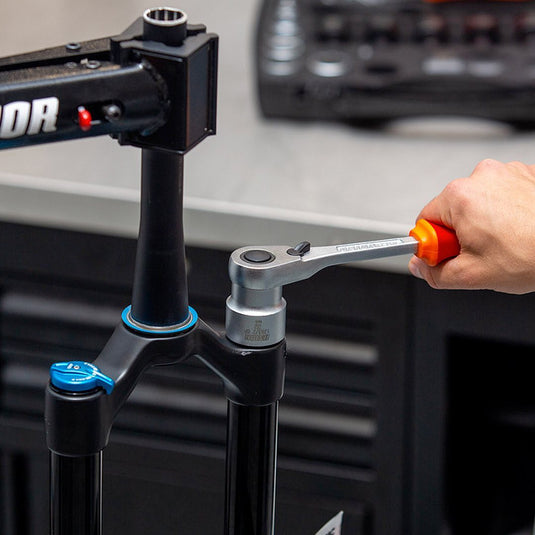Suspension fork mounted in a Unior workstand being serviced with a Unior ratchet, workshop bit set behind
