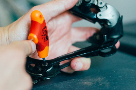 Unior 193HX-US 3 mm hex T-handle removing a jockey wheel bolt from a black rear derailleur cage held in hand