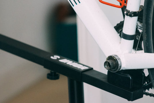 White hardtail mountain bike clamped in a Unior workstand by the seatpost, ready for Hollowtech II bottom bracket service