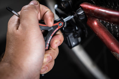 Mechanic using a Unior 178/2HX-US 5 mm Y-wrench on the rear derailleur limit screws of a red road bicycle