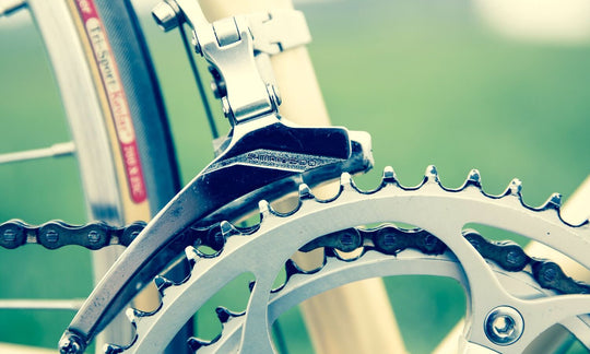 Close-up of a road bike front derailleur sitting just above the outer chainring, the adjustment this guide covers.