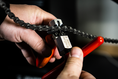 Mechanic hands using Unior Master Chain Tool 1647 to drive a pin through a bicycle chain in a workshop