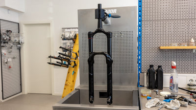 Suspension fork clamped in a Unior 990SIN stainless steel suspension sink, lower legs over the basin for a bath-oil service