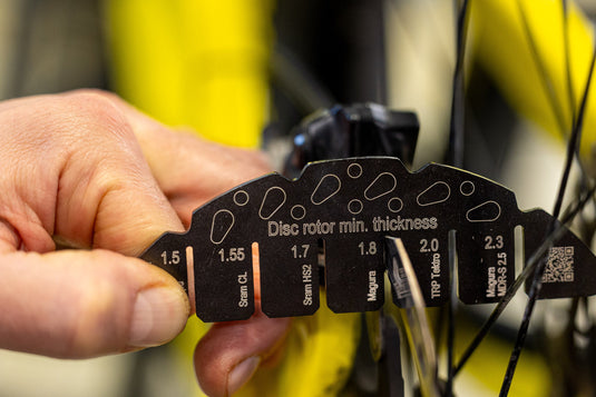 Checking a bicycle disc brake rotor with the Unior Rotor Wear Indicator.