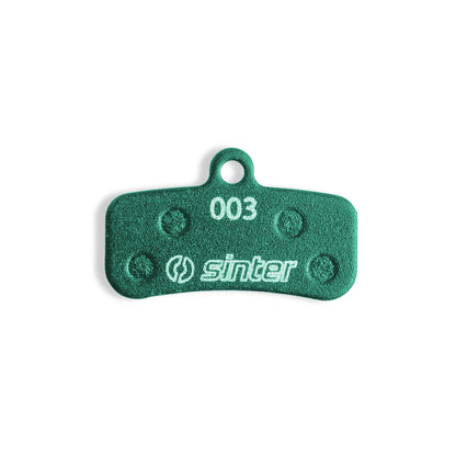 Sinter Green 003 disc brake pad back plate close-up, four damping pads around the 003 model stamp and Sinter logo