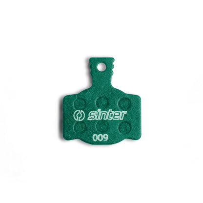 Sinter Model 009 Green disc brake pad backplate close-up, dimpled friction texture and 009 model stamp visible