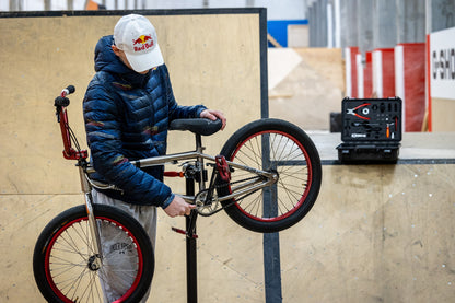 Rider adjusting a BMX bike on a repair stand with the open Unior BMX Tool Kit 1600BMX case on the ramp behind