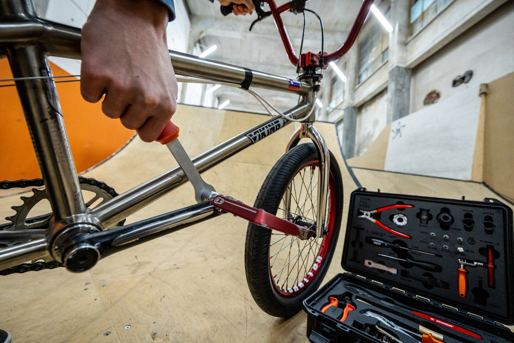 Removing a BMX pedal with the dipped-handle pedal wrench from the Unior BMX Tool Kit 1600BMX, open case alongside