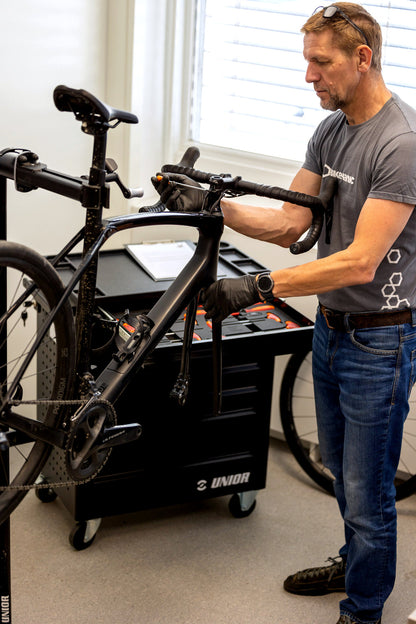 Mechanic using the Professional Mechanic Tool Carriage drawers while servicing a carbon road bike on the workstand