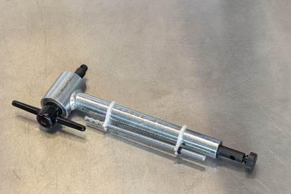 Hanger Genie 2.0 derailleur alignment tool resting on a scratched metal workshop bench, gauge rod extended