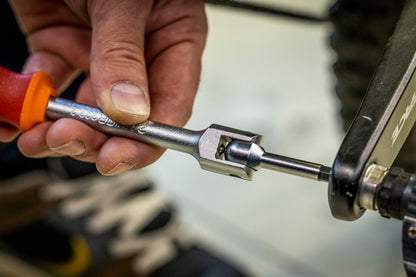 Mechanic engaging Unior Speed Pedal Wrench 8mm hex into a mountain bike crank arm, tool head visible at the pedal axle