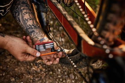 Mechanic using Unior Multitool EURO17 chain breaker on a mountain bike trailside, drivetrain visible