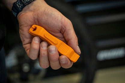 Pair of orange Unior 1657 tire levers interlocked for storage, held in a hand showing the spoke hook and embossed Unior logo