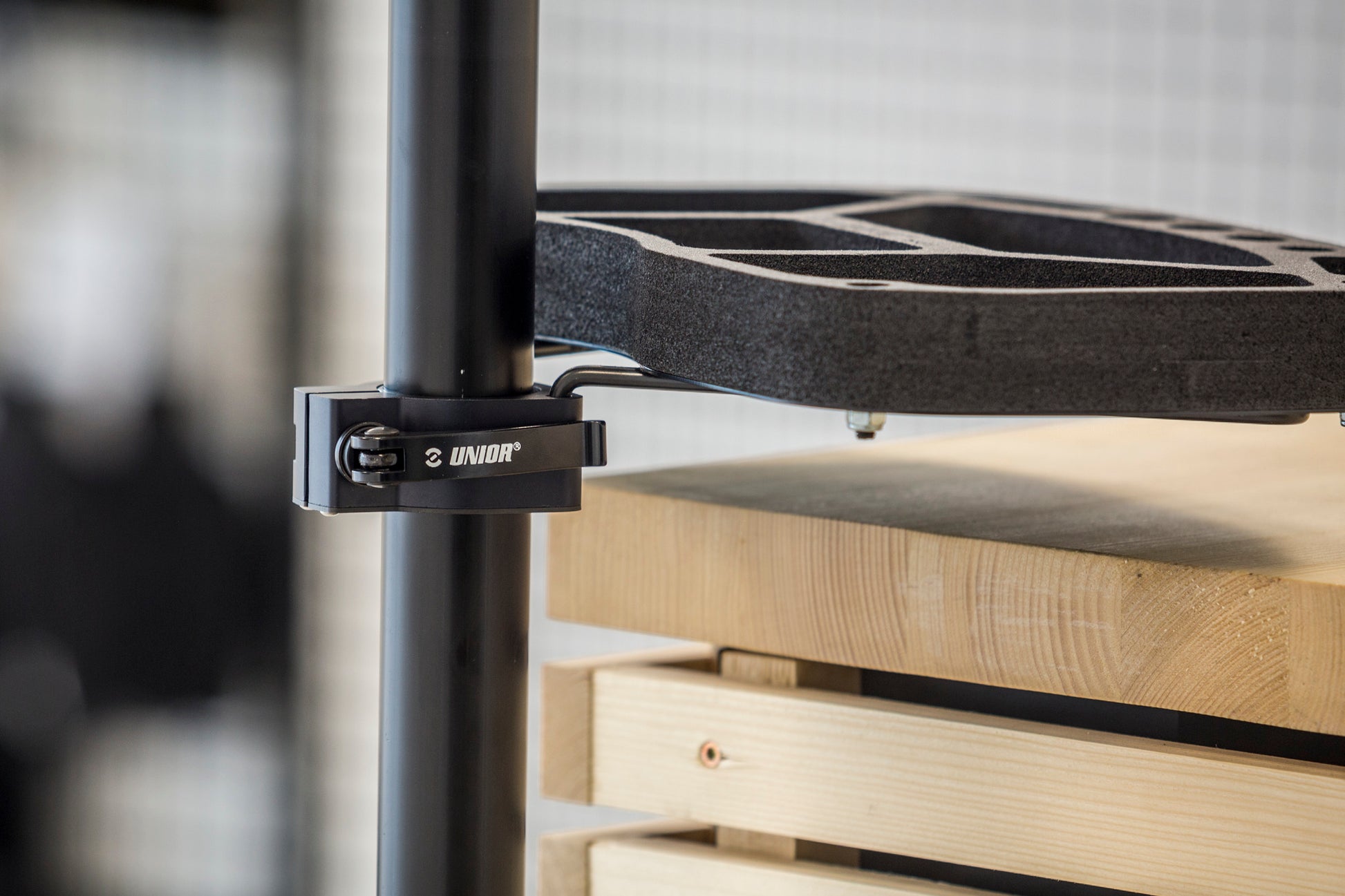 Unior Repair Stand Tool Tray Collar 1693.16 in use - quick-release collar clamped on the stand's upper tube, carrying the tool tray's support arms