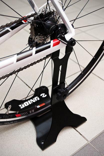 Unior 1693H display stand holding a road bike by the rear-axle slot, rubber-padded tines against the dropout, black finish