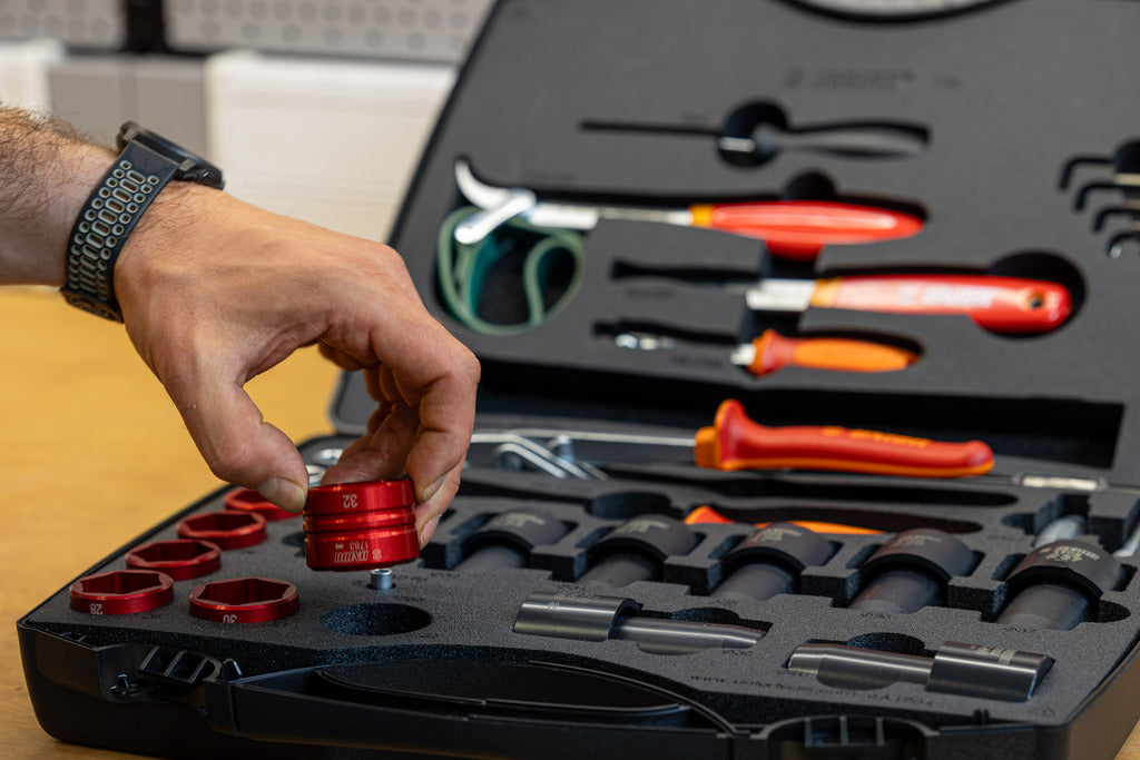 Mechanic selecting red Unior socket from Suspension Service Set 2.0 case, screwdrivers and dies visible inside lid