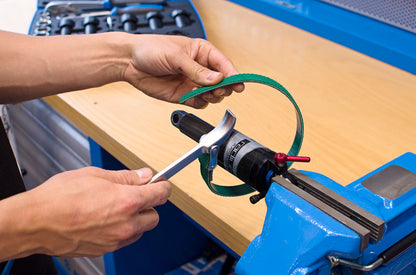 Threading the Unior 1705 strap wrench's green rubberized strap around a rear-shock air can held in a bench vise