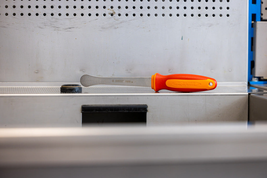 Unior Fork Dust Seal Remover resting on a stainless workshop bench with perforated tool-board behind