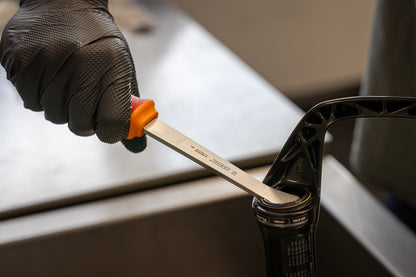 Gloved mechanic using Unior Fork Dust Seal Remover to lift the seal on a RockShox Solo Air suspension fork