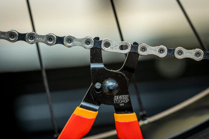 Master Link Pliers 1720/4DP opening a SRAM Eagle chain master link, tool spanning the chain at the rear wheel
