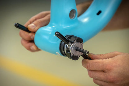 Mechanic pressing a bottom bracket bearing into a blue bicycle frame using the Unior 1721BB press kit