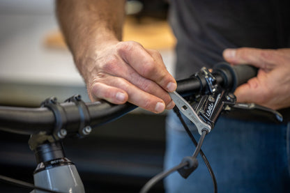 Mechanic using Unior 1760/2 flare nut wrench on a hydraulic brake banjo bolt at the lever of a mountain bike