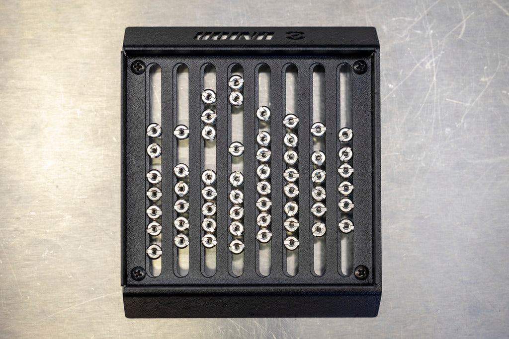 Unior Spoke Nipple Shuffler 1761 after a shake, silver spoke nipples lined up in the laser-cut grid slots
