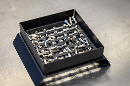 Unior Spoke Nipple Shuffler 1761 in use, silver spoke nipples settled in the slotted tray on a workbench