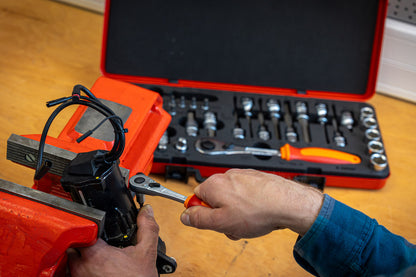 Mechanic using the Unior Master Bits and Sockets ratchet on a workpiece clamped in a vise, open case in the background