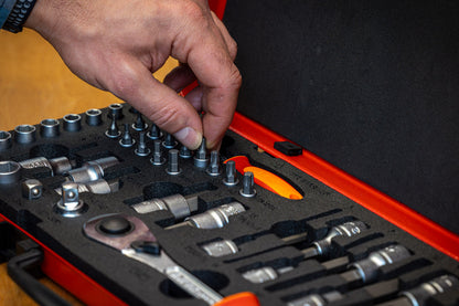 Mechanic selecting a hex bit from the Unior Master Bits and Sockets Set, foam tray of sockets and ratchet alongside
