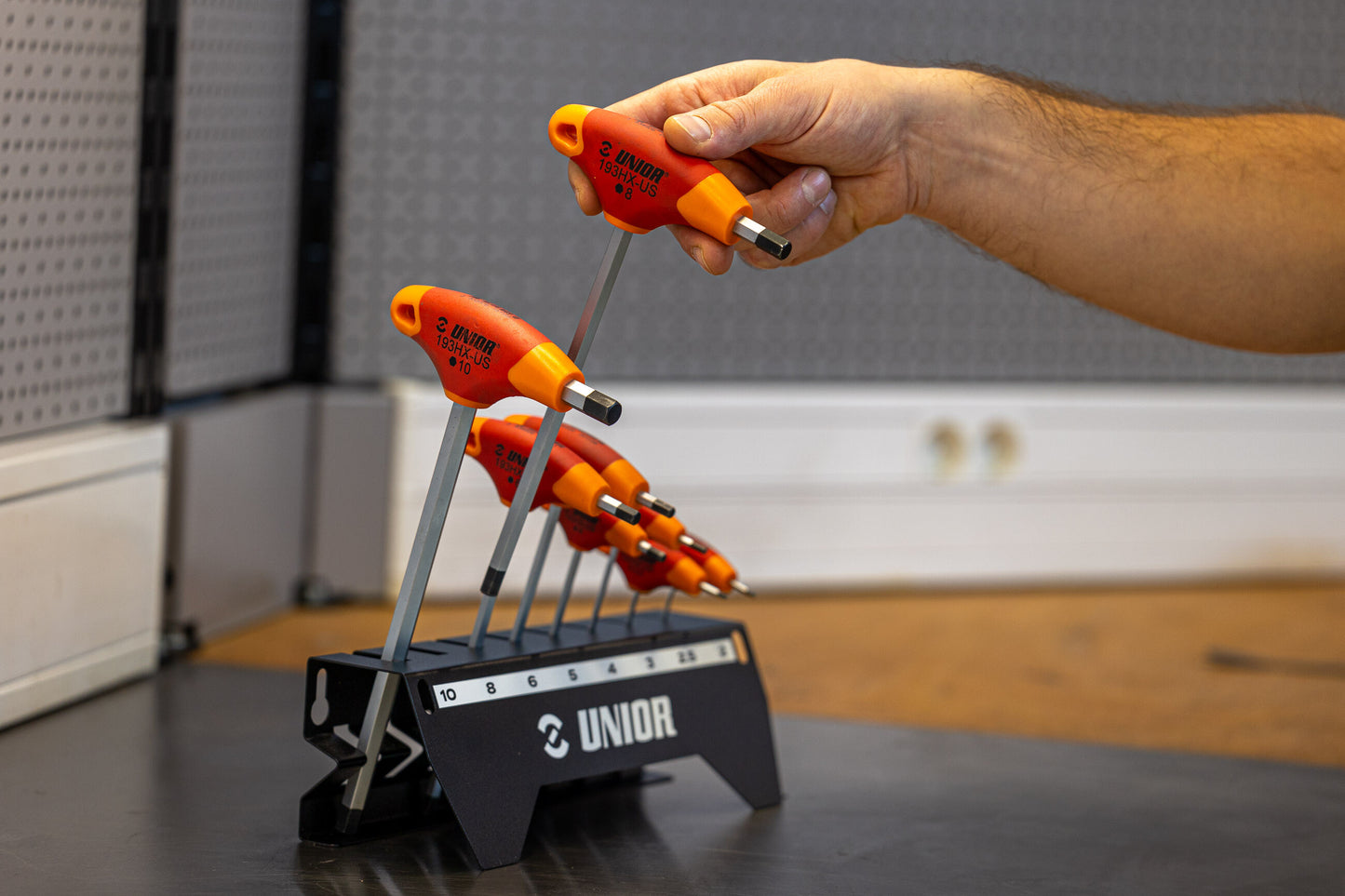 Mechanic lifting the 8 mm Unior 193HX-US T-handle hex wrench from the branded 2 to 10 mm size stand, red and orange grips