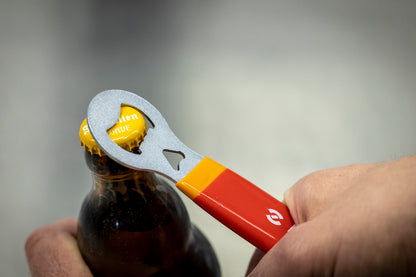 Unior Bottle Opener With Handle 45/2DP prying the yellow cap off a brown beer bottle in the hand