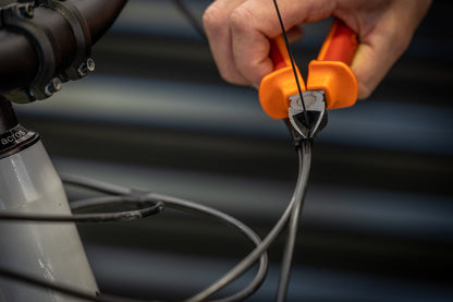 Mechanic using Unior 463/4BI-US flush cutters to trim a brake hose at the head tube of a mountain bike