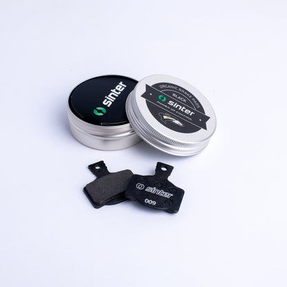 Sinter Model 009 Black organic disc brake pad pair beside aluminium tin packaging for Magura hydraulic calipers