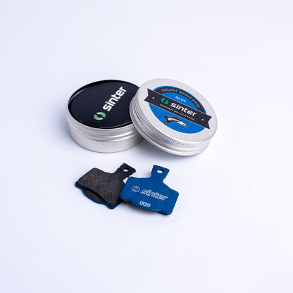 Sinter Model 009 Blue organic disc brake pad pair beside aluminium tin packaging for Magura hydraulic calipers