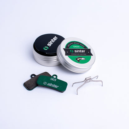 Sinter Green 003 organic brake pad pair with aluminum tin showing greyhound emblem and spring clip for Shimano Saint Zee