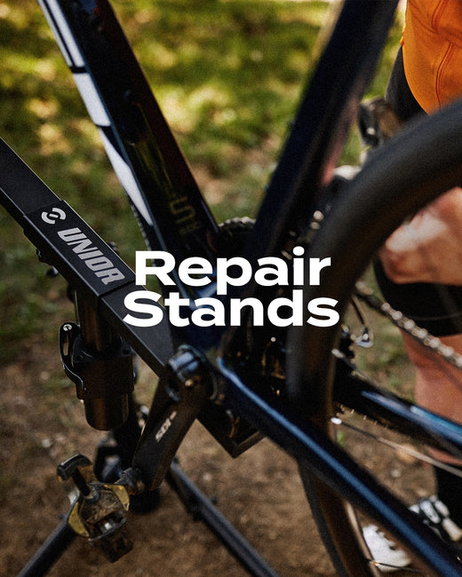Repair Stands category thumbnail with overlaid title, Unior workstand clamp holding a mountain bike on dirt