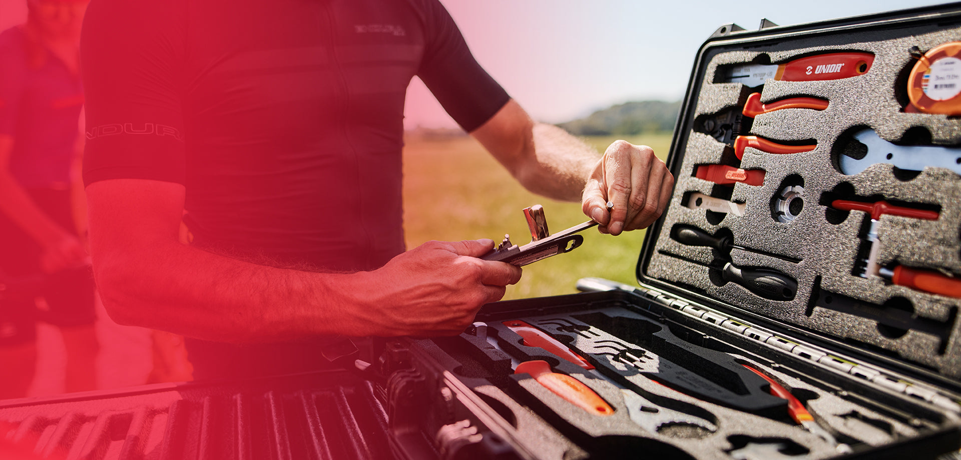 Mechanic checking a bicycle chain with a Unior tool beside an open Unior tool case — free Check-Up Kit promo