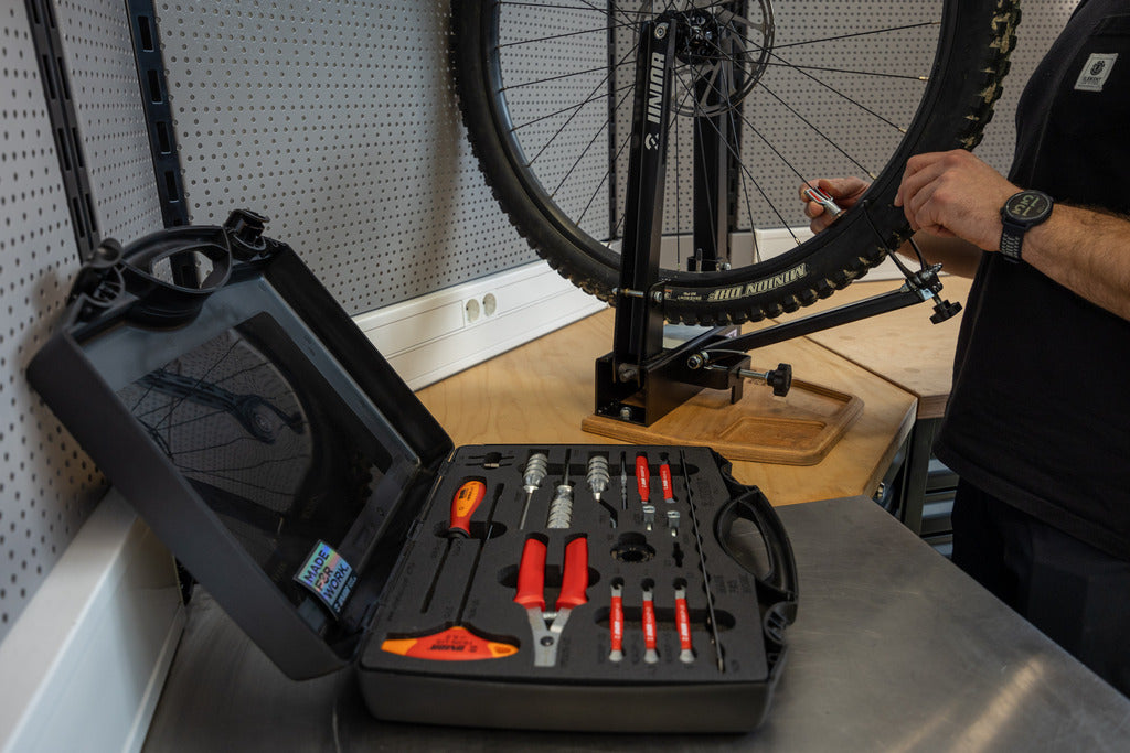 Master Wheel Building Kit 1754 open on a bench beside a wheel in a Unior truing stand; the stand is not part of the kit