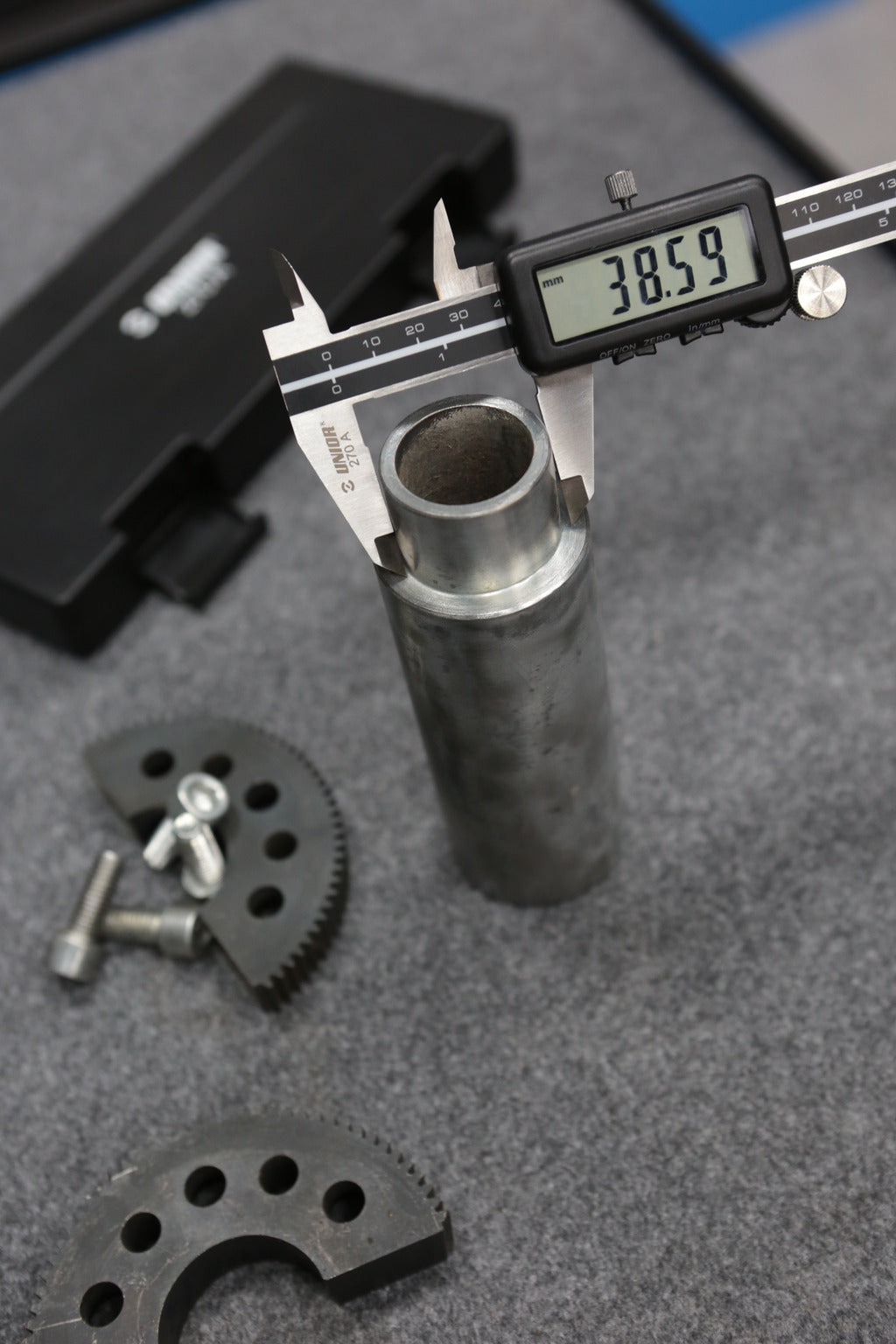 Unior 270A digital caliper measuring a steel tube outer diameter 38.59 mm on a workshop bench