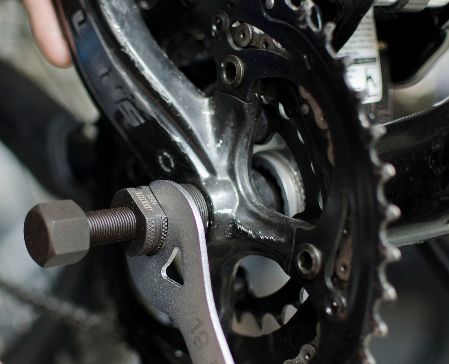 Unior 1662/4 tapered crank puller threaded into a crank arm, held with a 19 mm wrench, centre rod extended