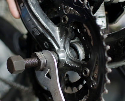 Unior 1662/4 tapered crank puller threaded into a crank arm, held with a 19 mm wrench, centre rod extended