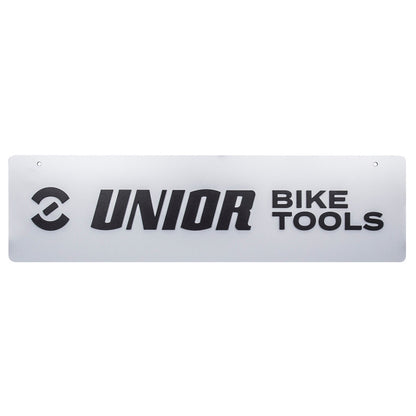 Unior logo panel, front view: silver-gray sign with black Unior symbol, UNIOR BIKE TOOLS lettering and two mounting holes