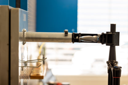 Side view of Unior 990SIN sink fork-clamp arm extended from the panel, holding a dropper post for workshop service