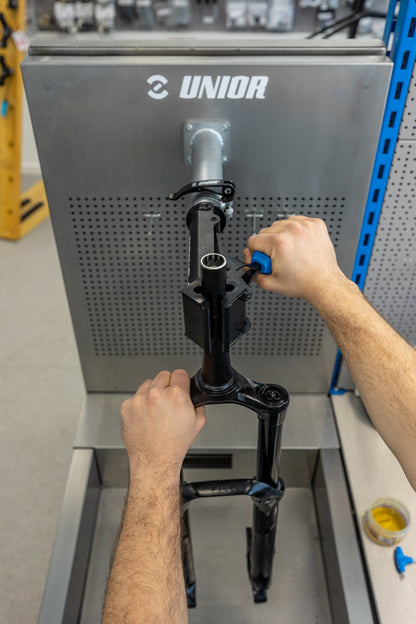 Mechanic loosening the top cap of a mountain bike fork held in the Unior 990SIN suspension sink clamp