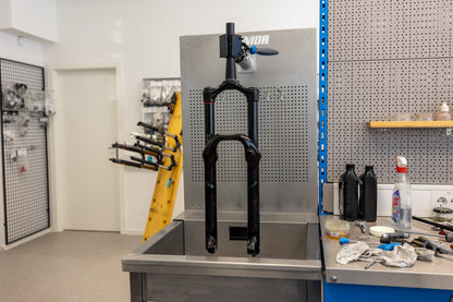 Mountain bike fork mounted in Unior 990SIN sink clamp, lower legs hanging into the basin ready for oil bath service