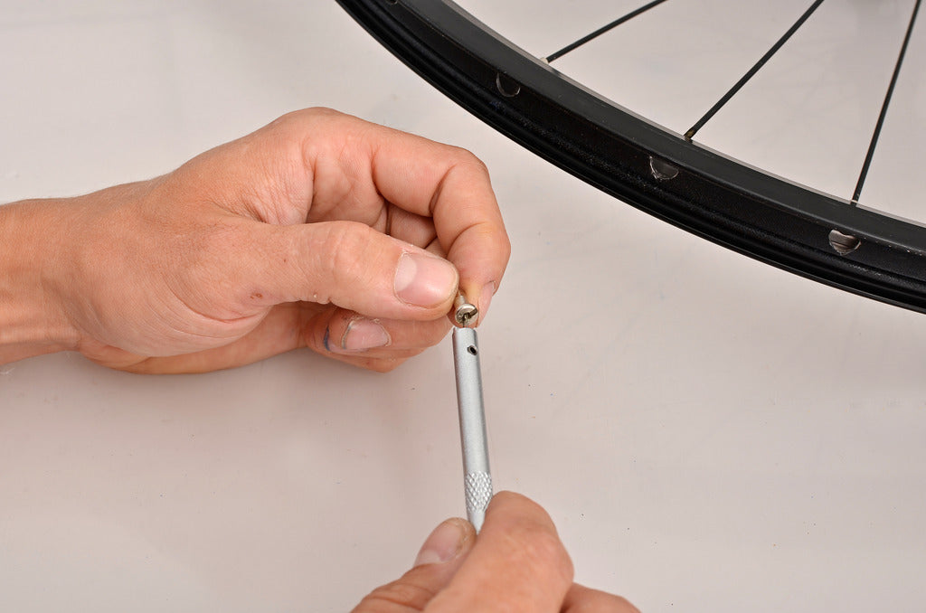 Loading a spoke nipple into the spring-loaded tip of the Unior 1751/2T nipple insertion tool