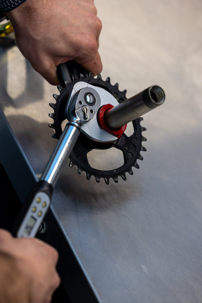 Mechanic using Unior 1723.SDL lockring tool with digital torque wrench to install a direct-mount chainring on a crankset